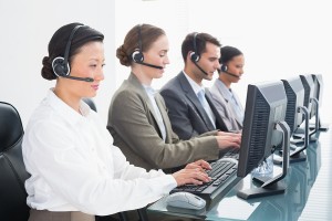 Business people with headsets using computers in office.